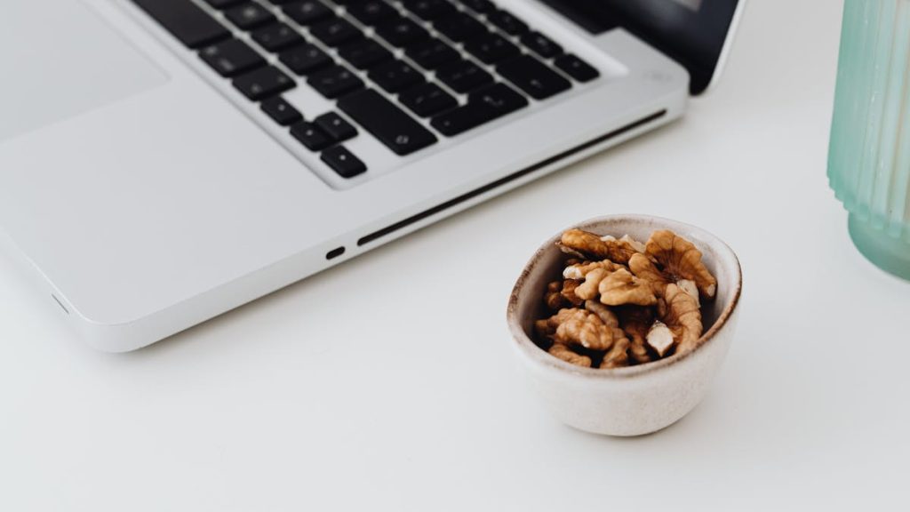 Laptop with a bowl of walnuts on a desk — high-protein snack under 100 calories